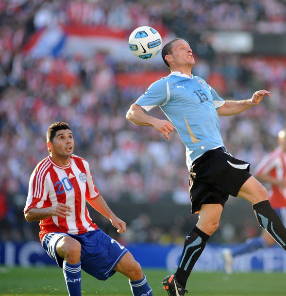 Foto Diego Perez (kanan) menyundul bola yang dibayang-banyangi pemain Paraguay, Nestor Ortigoza