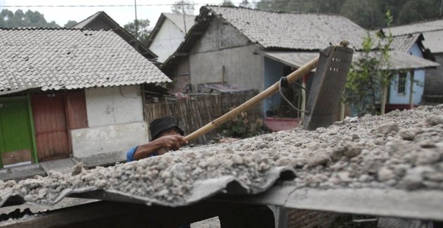 Gambar Foto Warga Membersihkan Kerikil yang Ada di Atas Atap Rumah