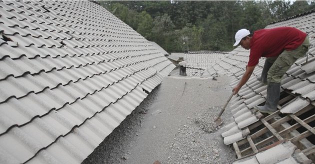 Gambar Foto Warga Membersihkan Kerikil yang Ada di Atas Atap Rumah