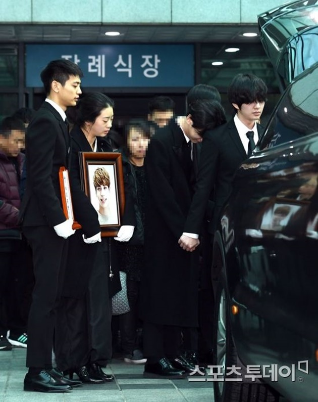Gambar Foto Onew menggenggam erat tangan Key yang menangis di pundaknya usai peti jenazah Jonghyun dimasukkan ke dalam mobil.