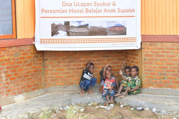 Gambar Foto Ini adalah potret anak-anak Sapalek yang terlihat bahagia berada di depan sekolah mereka, Honai Belajar Anak.