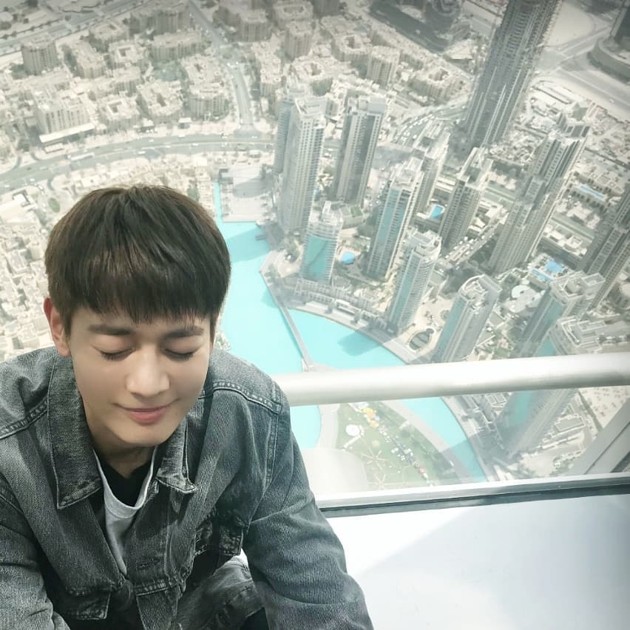 Gambar Foto Tak mau kalah, Minho ikut berpose memperlihatkan ketinggian gedung Burj Khalifa