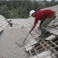 Warga Membersihkan Kerikil yang Ada di Atas Atap Rumah