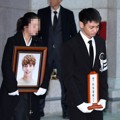 Kakak kandung Jonghyun terlihat menangis saat membawa foto sang adik di prosesi pemakaman.