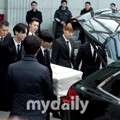 Para personel SHINee dan Super Junior memasukkan peti jenazah Jonghyun ke dalam mobil.