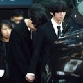 Onew menggenggam erat tangan Key yang menangis di pundaknya usai peti jenazah Jonghyun dimasukkan ke dalam mobil.